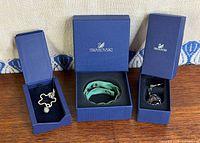 Three Swarovski boxes open showing bracelet and two keychains