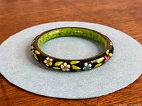 Top view of entire bangle showing exterior floral cloisonné and green interior