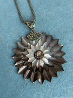 Close-up of pendant front detailing carved mother of pearl petals, central disk, and sterling bail