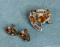 Front view of brooch and earrings showing thistle design and citrine stones