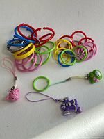 Group of plastic rings and three phone charms on white background