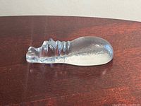 Side view of clear frosted glass hippo sculpture on wood surface
