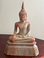Front view of soapstone Buddha statue seated on tiered base