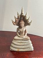 Front view of carved stone Buddha statue on coiled serpent base with seven-headed hood