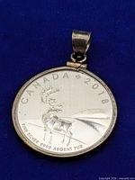 Front view of coin pendant showing caribou design and markings