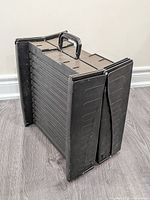 Folded black plastic tri-fold pet ramp standing upright showing handle and side rails