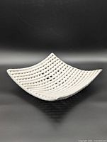 Angled view of white ceramic woven-look tray showing concave profile