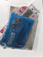 Front view of sealed package showing blue hair net sachet and white comb