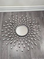 Full view of starburst wall mirror on floor showing design and condition