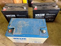 Front view of three Weize batteries showing two black AGM units and one blue gel unit