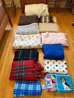 All thirteen blankets, throws and mattress topper laid out on floor