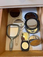 Drawer containing assorted handheld and compact mirrors