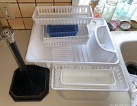 All items grouped on countertop including dish rack, paper towel holder, white baskets, blue bin, clear bin