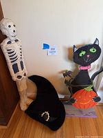 Overall view showing wooden cat treat greeter, paper-mache skeleton and velvet witch hat