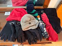 All items spread on surface: three caps, two umbrellas, two pairs gloves, scarf