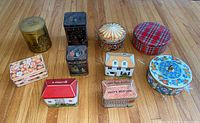 Group shot of ten decorative metal tins arranged on floor
