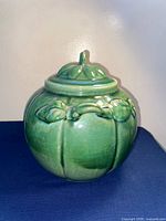 Front view of green gourd-shaped pottery jar with lid