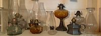 Group view of eight oil lamps and four spare chimneys