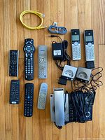 Front view of nine remotes, cordless phone set with base and cradles, two AC adapters, Ethernet and phone cables