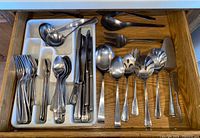 Drawer view showing entire assortment of flatware organized in tray with serving utensils on right