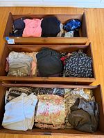 Three dresser drawers filled with folded women’s clothing in various colours and patterns