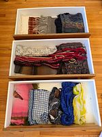 Three open drawers showing multiple folded scarves of various colours and textures