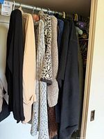 Multiple sweaters and cardigans on closet rod