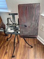 Full view of stand showing wood rest, metal springs, tripod legs on wheels