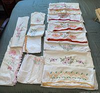 Overview of all pillowcases laid out on bed showing quantity and variety of embroidery