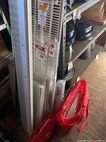 Vertical view of bundled Elfa wall standards, loose ventilated shelves, red Elfa tote bags