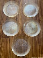 Five matching glass starburst plates displayed on wooden floor