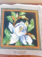 Front view of completed floral needlepoint canvas showing full design and untrimmed edges