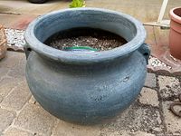 Full view of round blue-gray clay pot showing shape and soil inside