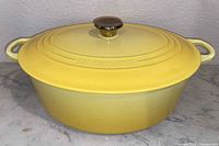 Side view of yellow Le Creuset oval Dutch oven with lid