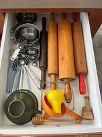 Drawer overview showing rolling pins, measuring cups/spoons, funnel, juicer, honey dipper, tamper