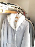 Closet rod with plush fleece hoodie and hats on shelf
