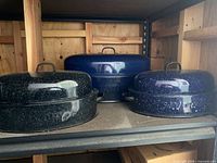 Three Savory enamel roasters with lids on shelf