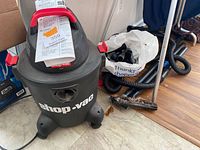 Full view of Shop-Vac with manual on top, accessory bag and hoses beside