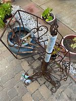 Full view of spiral plant stand showing rust and structure