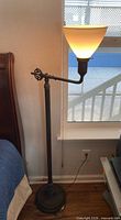 Full view of floor lamp beside bed showing height and shade lit