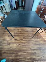 Overall view of black folding card table with legs extended