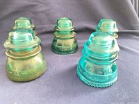 Five teal Hemingray-42 insulators front view showing color and condition