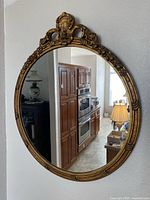 Full view of oval gold mirror hanging on wall