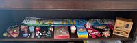 Shelf view with kite kits, puzzle, cards, wooden box, basket of apples and assorted figurines