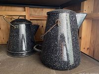 Two black speckled enamelware pieces on shelf