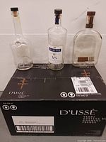 Three empty glass bottles on top of D'USSÉ box