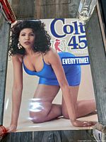 Full view of Colt 45 advertising poster on table