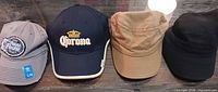 Front view of all four caps lined up: grey Adidas NCAA Final Four cap, navy Corona cap, tan cadet cap, black cadet cap