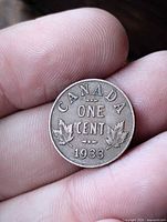 Obverse side of 1933 Canadian one cent coin in hand, showing denomination and maple leaf design