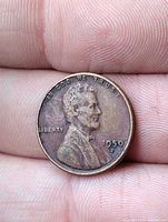 Obverse of 1950-D Lincoln Wheat Cent held between fingers, displaying date, "D" mint mark, and Lincoln portrait